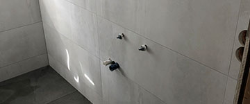 Rechte Seite eines Badezimmers mit weißen Wandfliesen und grauen Bodenfliesen von BekOli Fliesenverlegung